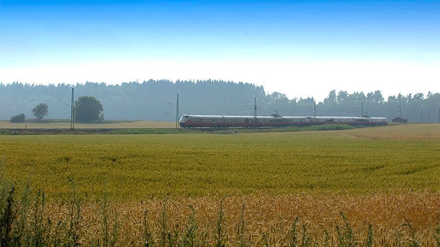 Bilde av et tog. I forgrunn er det en grønn åker.